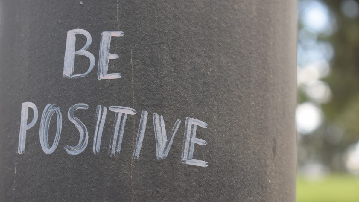 Be positive written on a dark pole.
